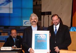 Dr. Bernd Kathe, Generalbevollmächtigter des KSA, hält eine gerahmte Urkunde in den Händen, neben ihm steht ein weiterer Herr.